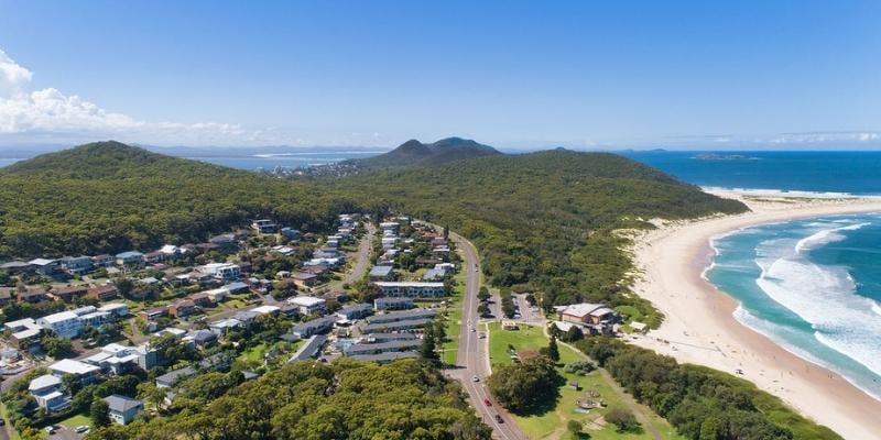 Story-based intervention - My Holiday at Seaside Holiday Resort in Fingal Bay  -  Aerial view of resort across from Fingal Beach and the Surf Life Saving Club with Mt Tomaree, Tomaree National Park, S